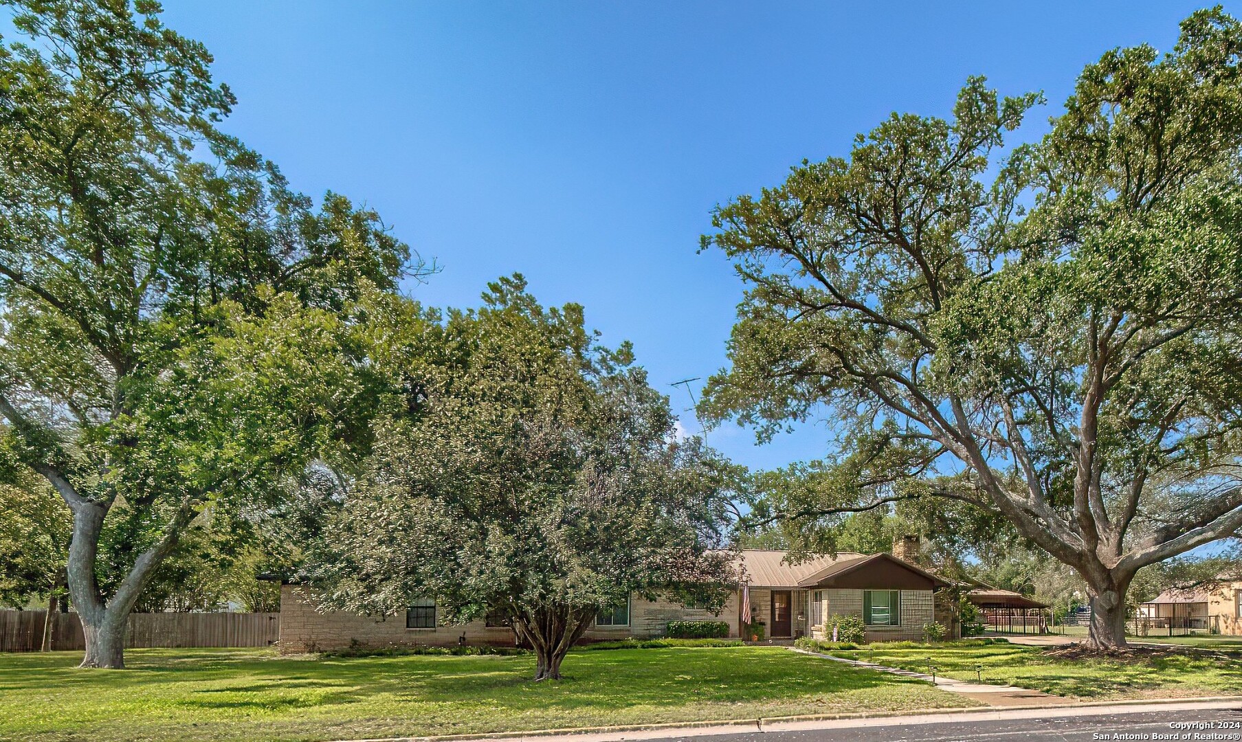 a view of a big house with a big yard and large trees