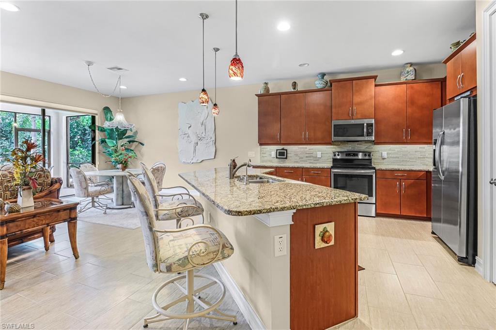 a kitchen with stainless steel appliances granite countertop a kitchen island a stove a sink a dining table and chairs