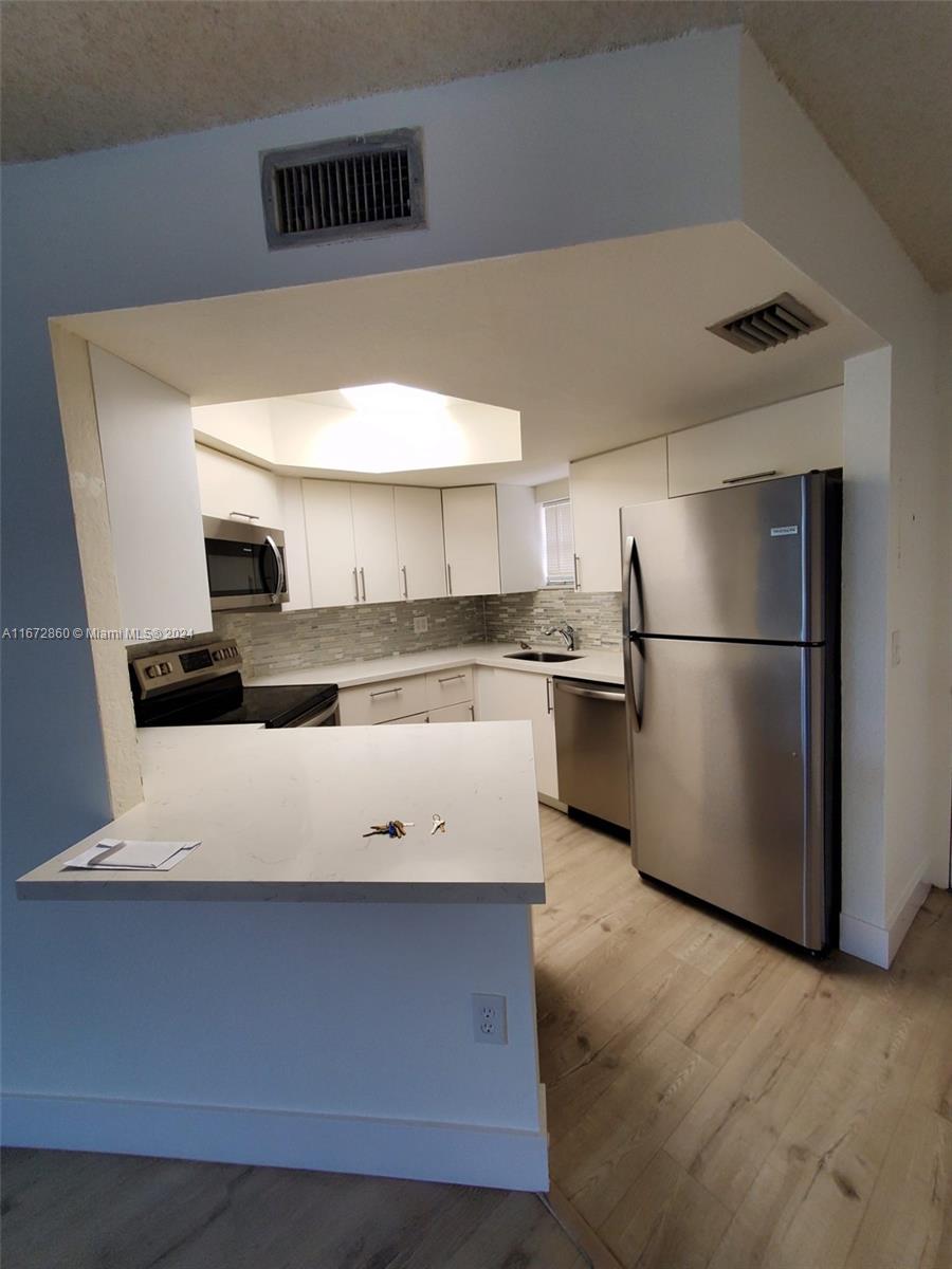 a kitchen with stainless steel appliances granite countertop a refrigerator a stove and a microwave