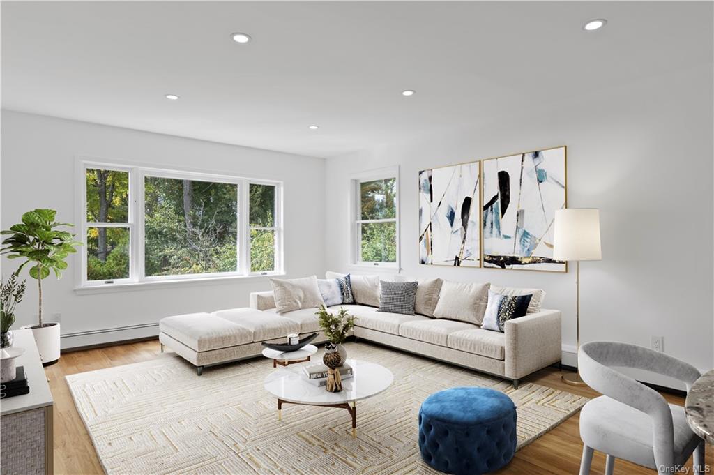 Living room with baseboard heating and light hardwood / wood-style flooring