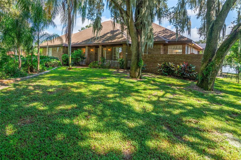 a view of house in front of a big yard with large trees