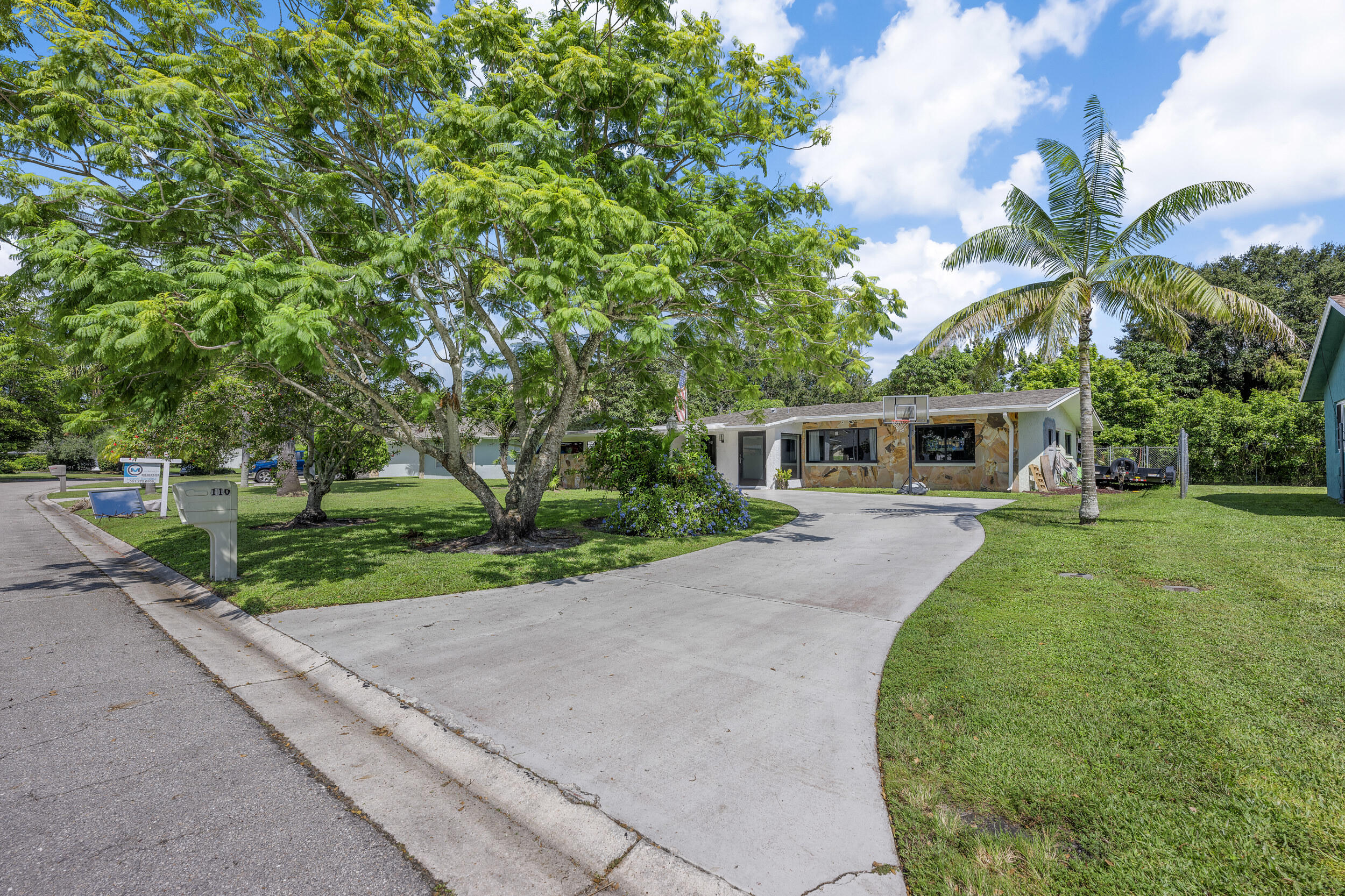 a front view of a house with a garden and trees