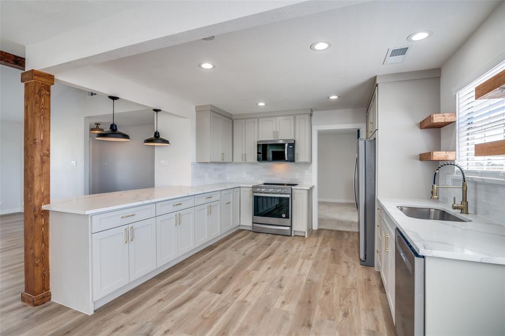 a kitchen with granite countertop a sink stainless steel appliances and cabinets