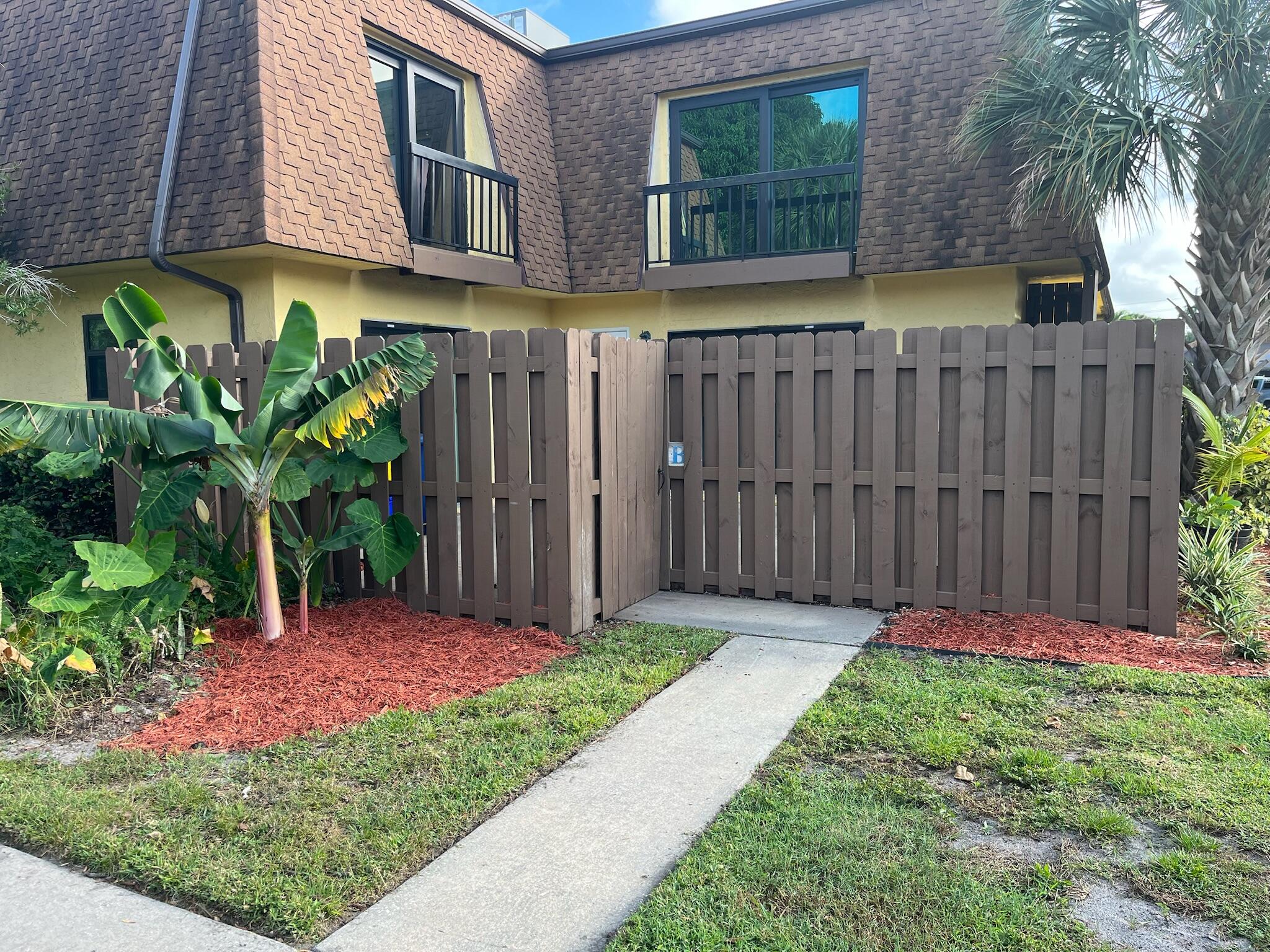 a view of backyard with potted plants and wooden fence