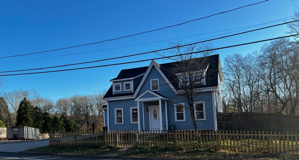 a view of a big house with wooden fence and large trees