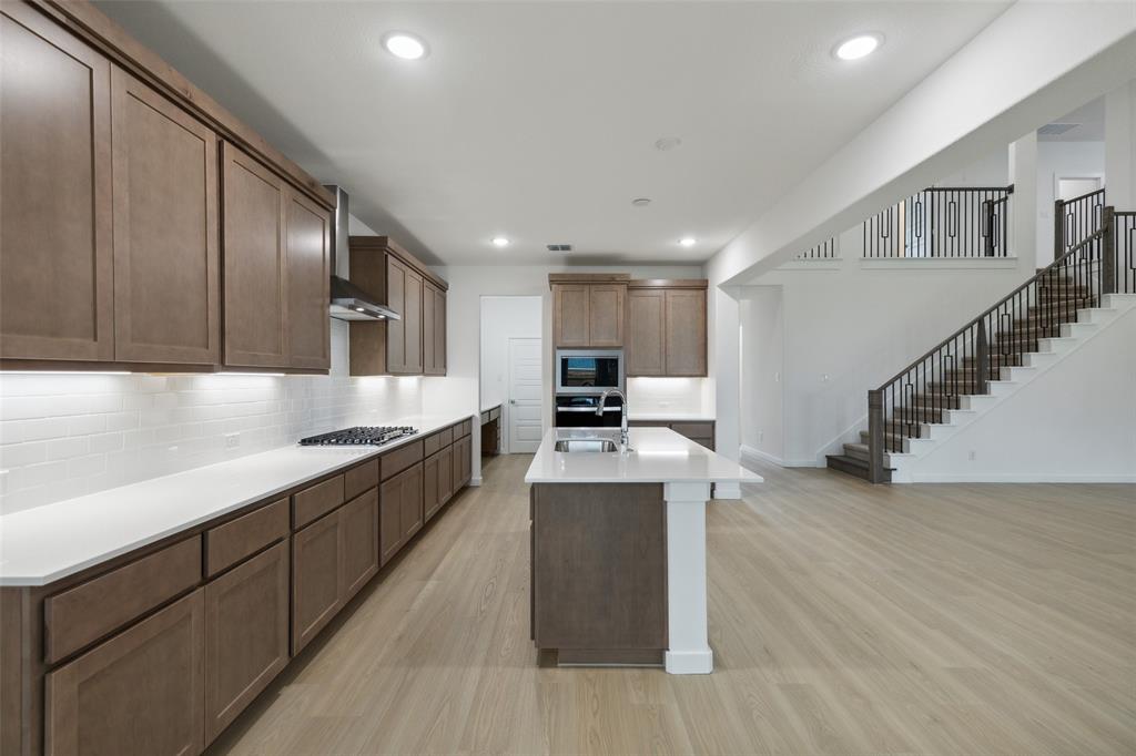 a large kitchen with stainless steel appliances granite countertop a lot of counter space and wooden floor