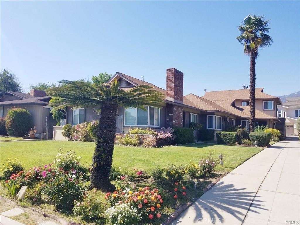 a front view of a house with a yard and potted plants