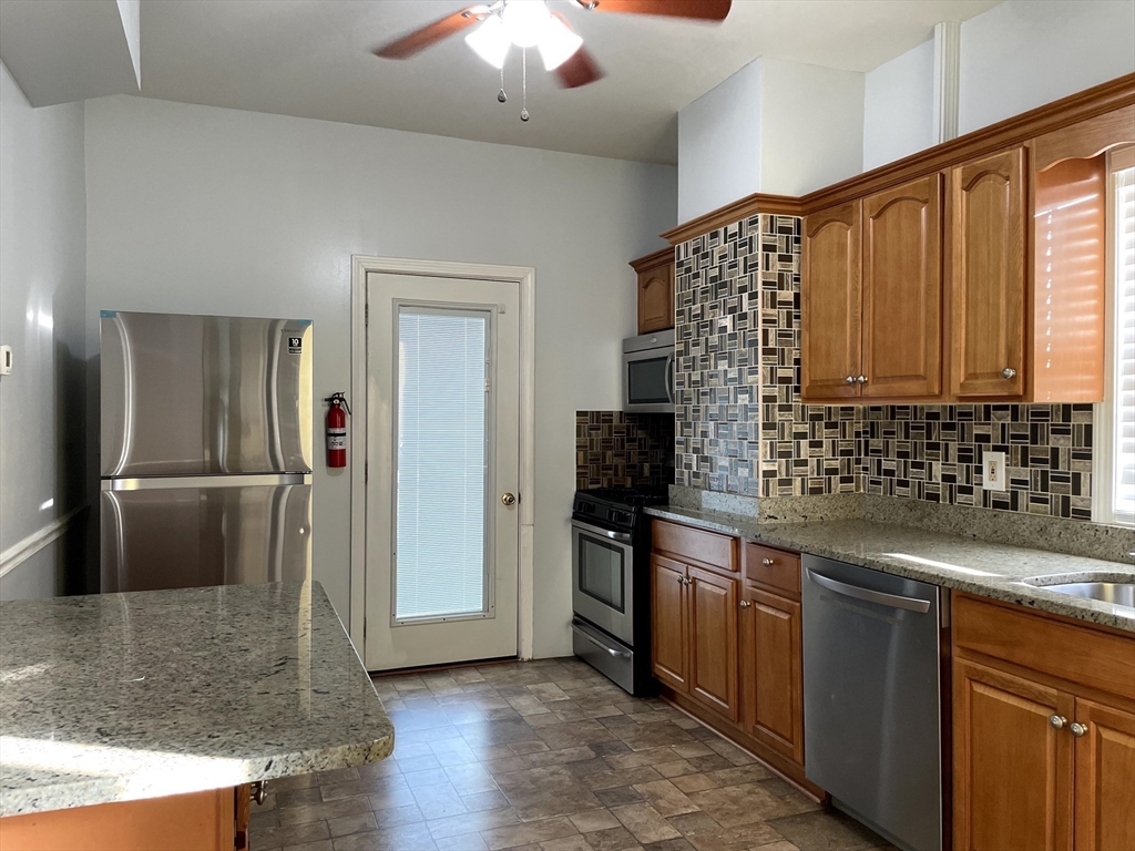 a kitchen with stainless steel appliances granite countertop a sink and a refrigerator