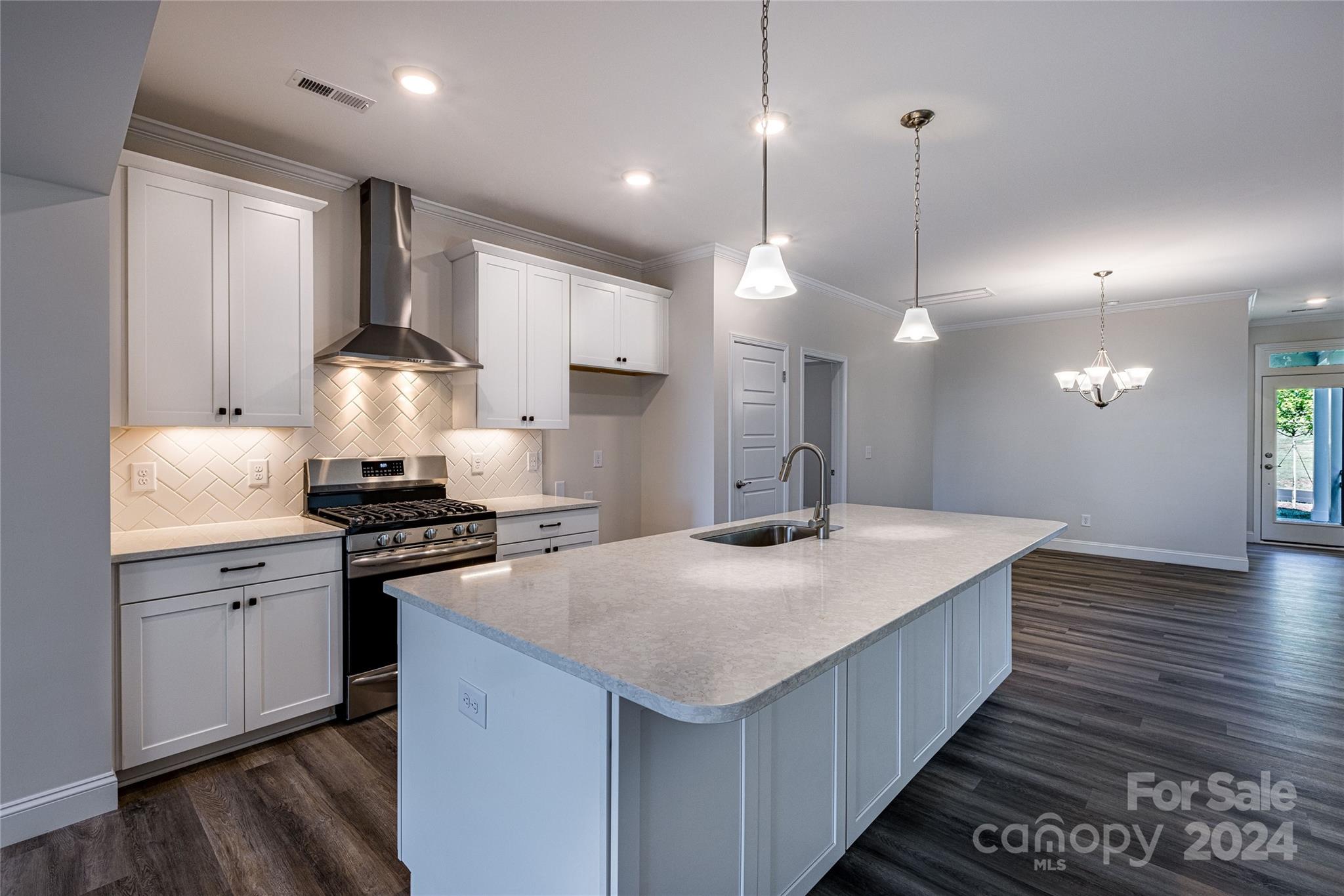 a kitchen with stainless steel appliances granite countertop a sink a stove and a wooden floors