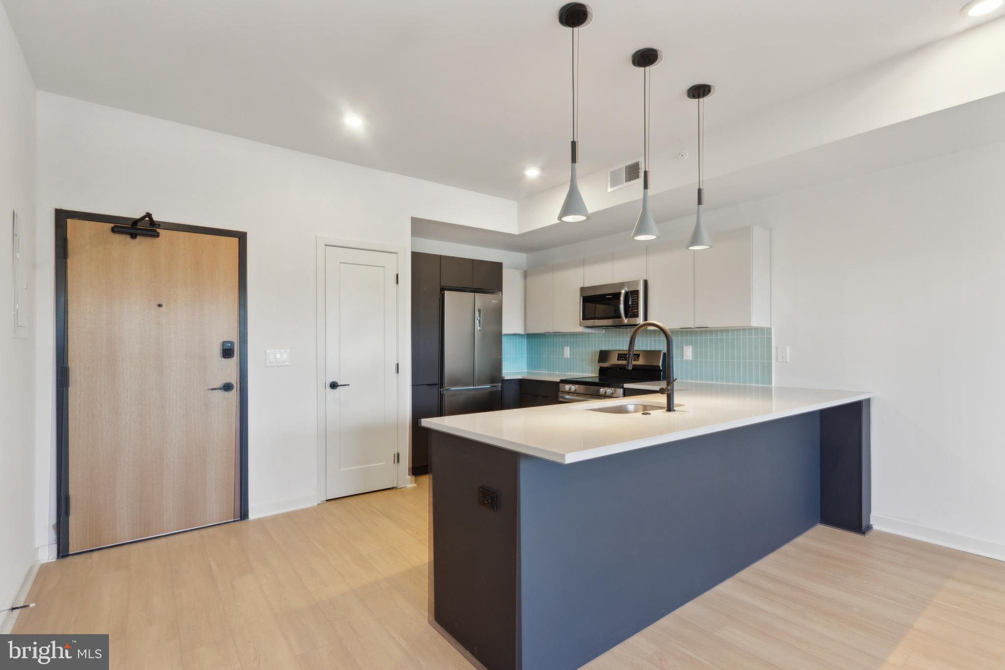 a kitchen with kitchen island a sink a counter top space stainless steel appliances and a chandelier