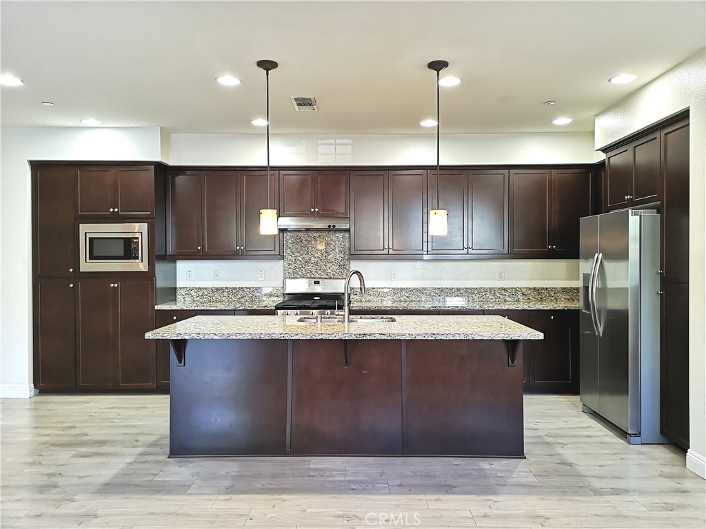 a kitchen with kitchen island stainless steel appliances a sink stove and refrigerator