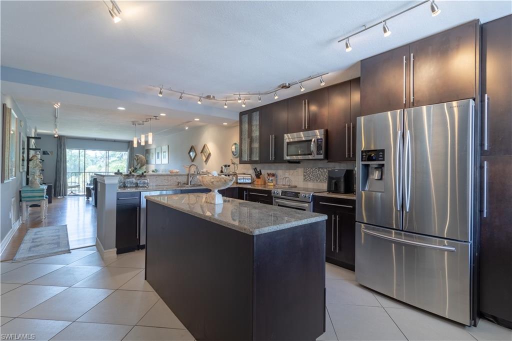 a kitchen with stainless steel appliances granite countertop a refrigerator a stove a sink and a refrigerator