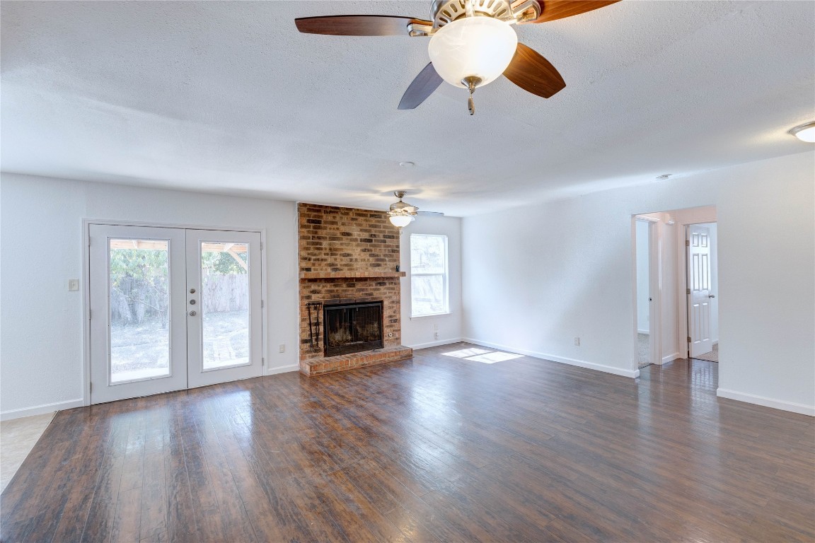 a view of an empty room with wooden floor and a fireplace