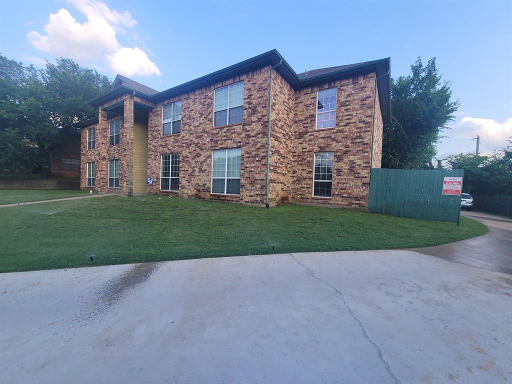 a view of a brick house next to a yard with big trees