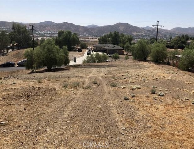 a view of a dry field with mountains in the background