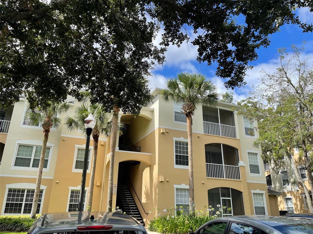 a front view of a multi story residential apartment building with yard and parking space