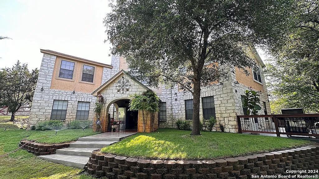 a front view of a house with a garden and trees