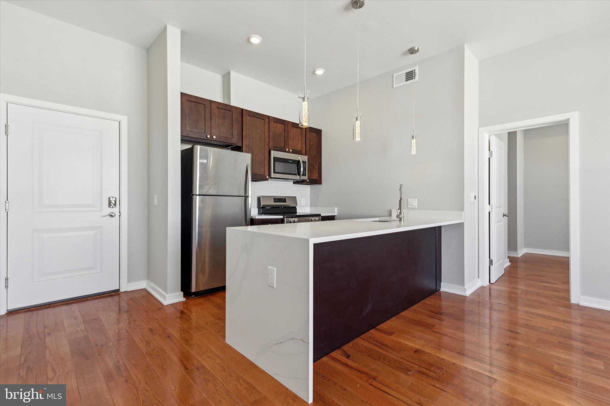 a kitchen with kitchen island a refrigerator and a sink