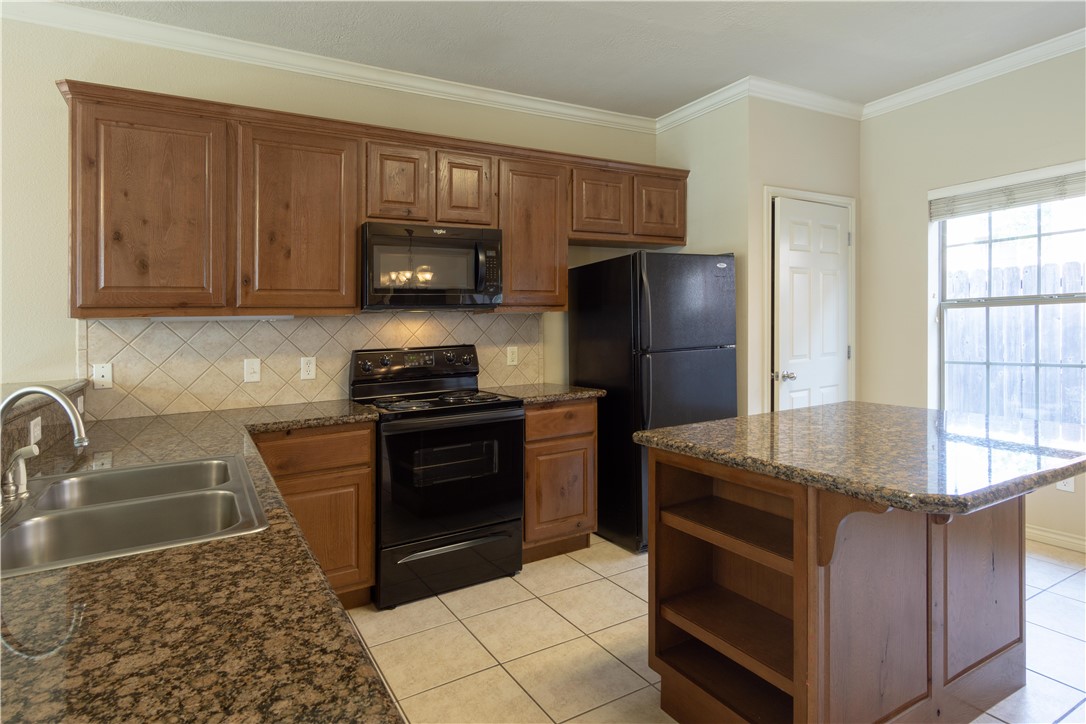 a kitchen with granite countertop a refrigerator stove and microwave