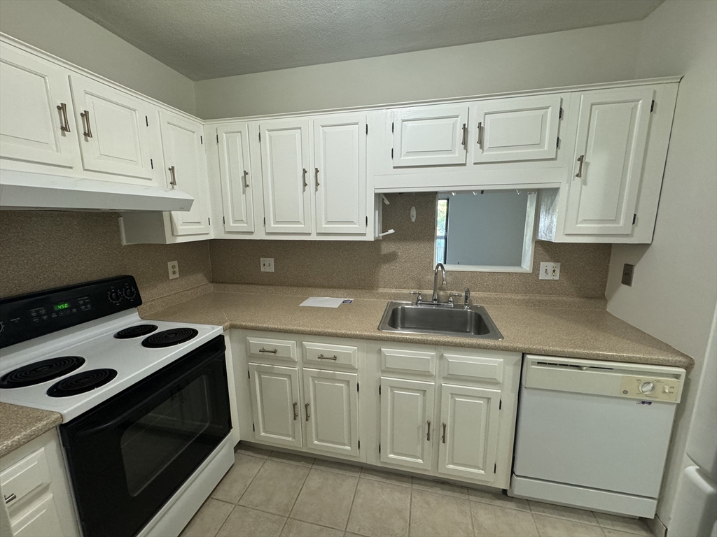 a kitchen with white cabinets and appliances