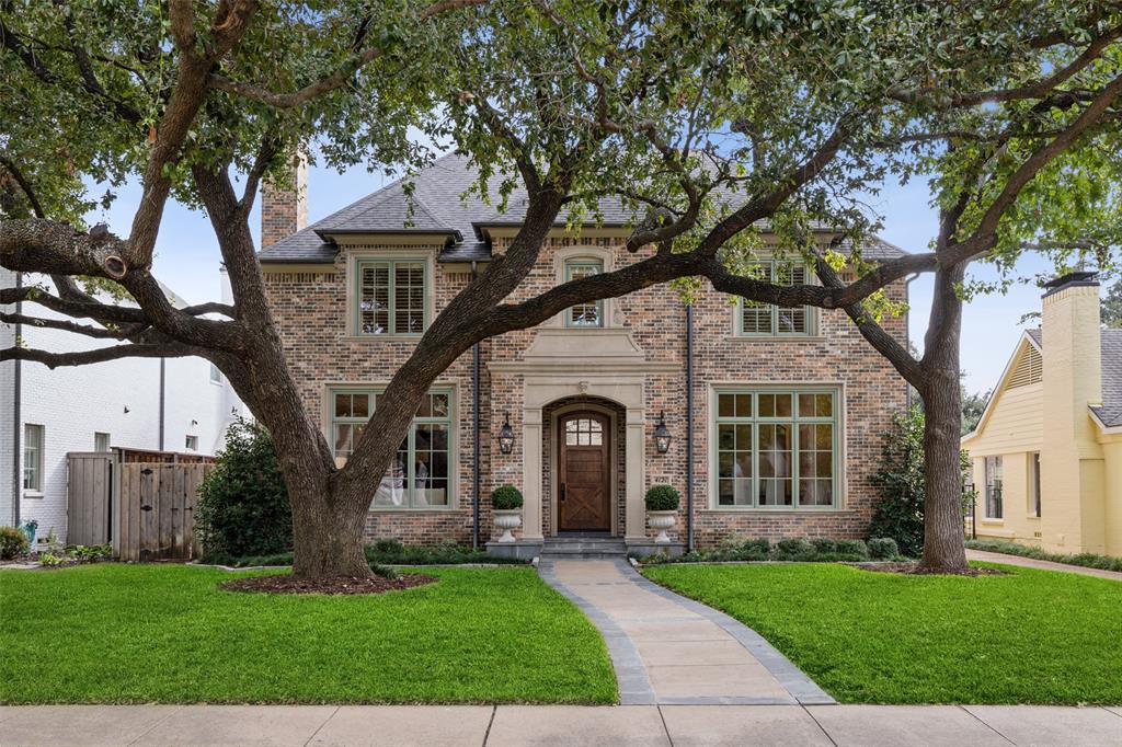 a front view of a house with a garden and trees