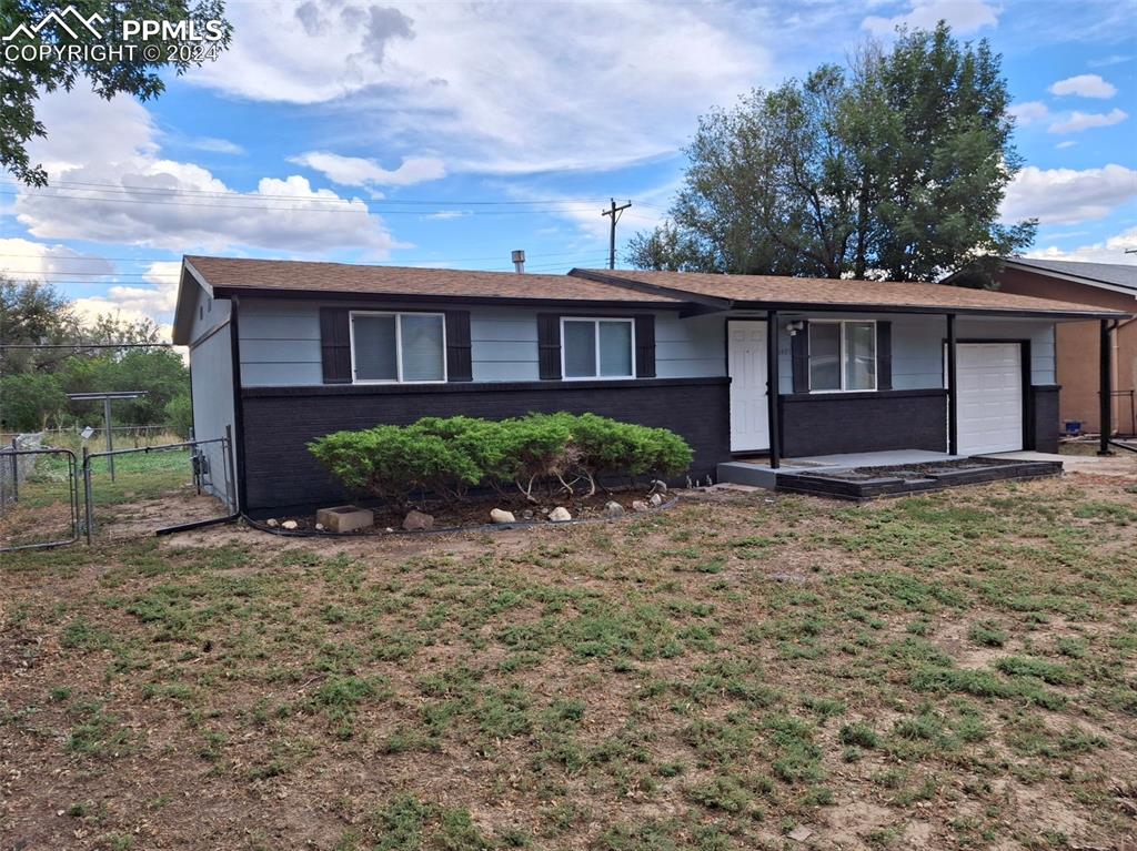 Single story home featuring a garage and a front lawn