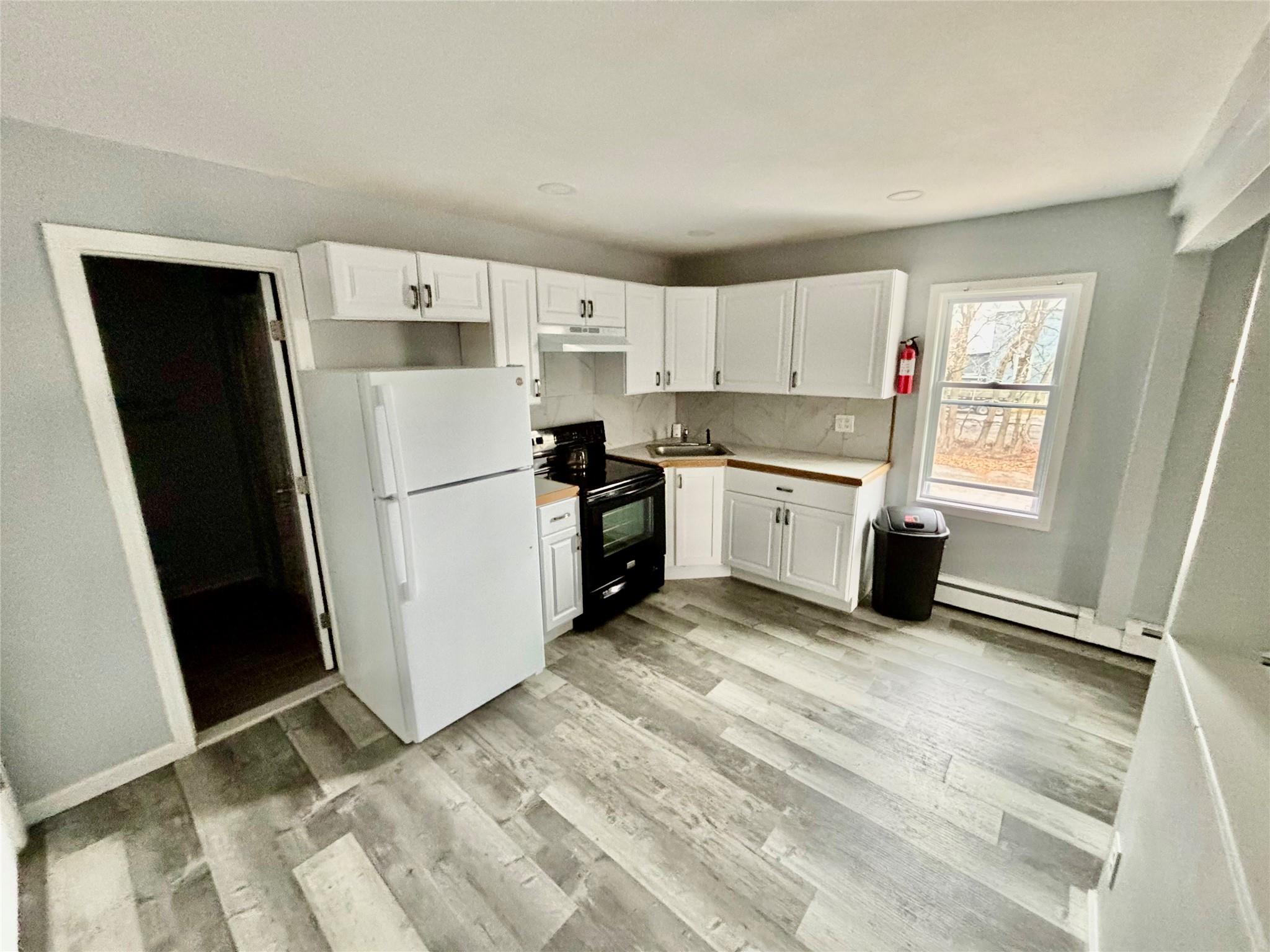 a kitchen with a refrigerator a stove top oven and cabinets