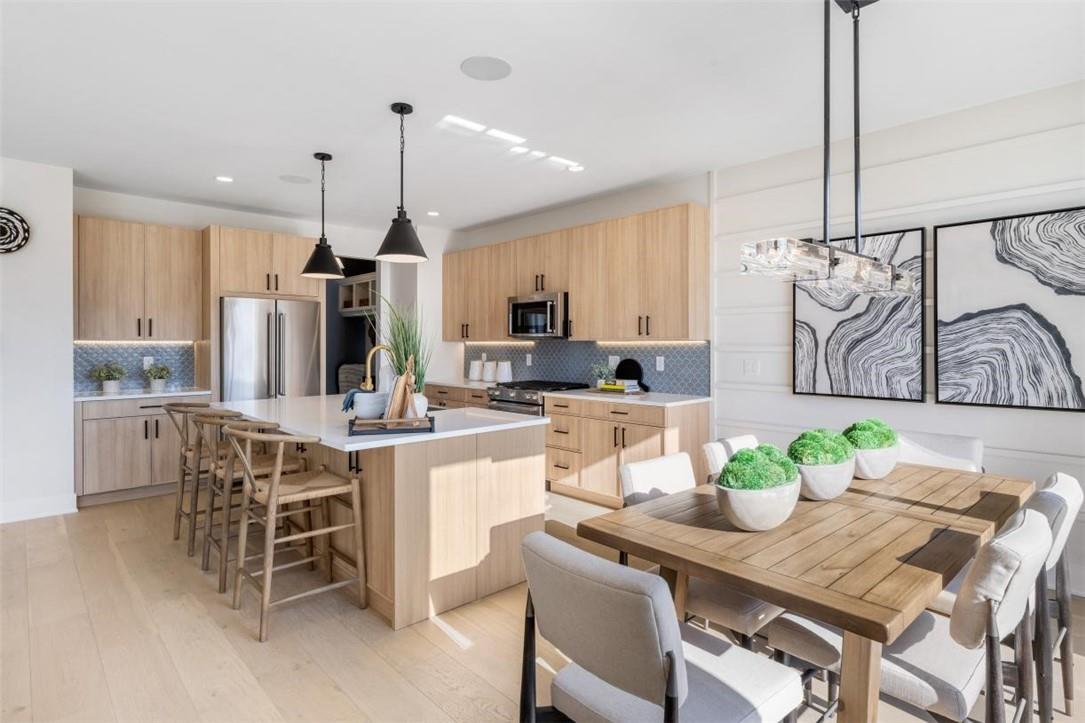 a kitchen with stainless steel appliances kitchen island granite countertop a table chairs and a refrigerator