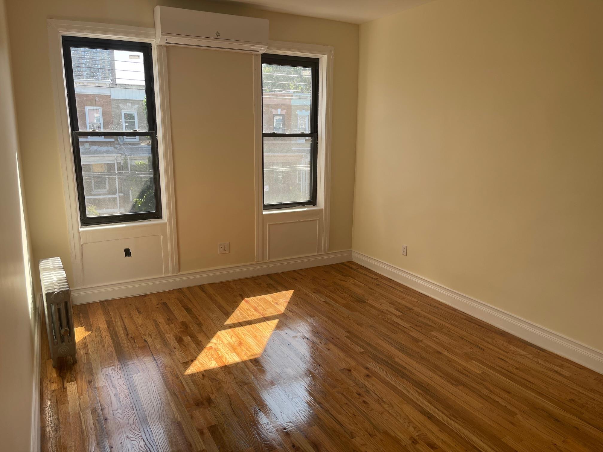 Unfurnished room with radiator, hardwood / wood-style floors, and a wall mounted air conditioner