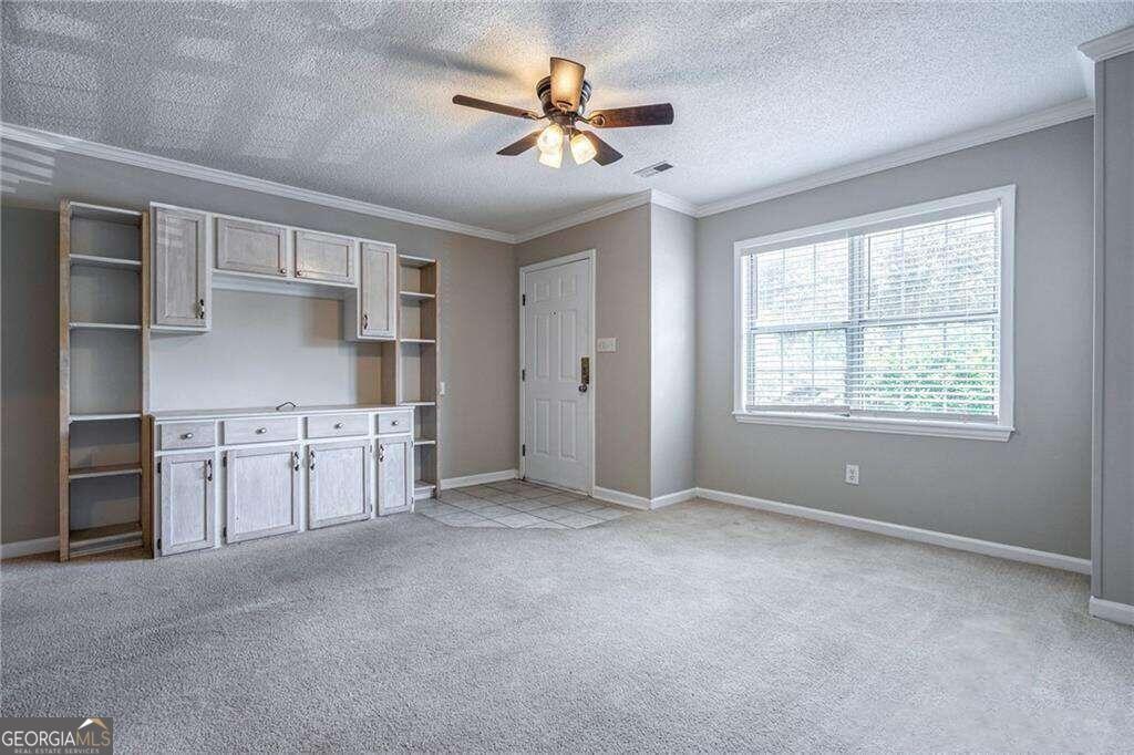 a view of a kitchen with cabinet a ceiling fan and windows