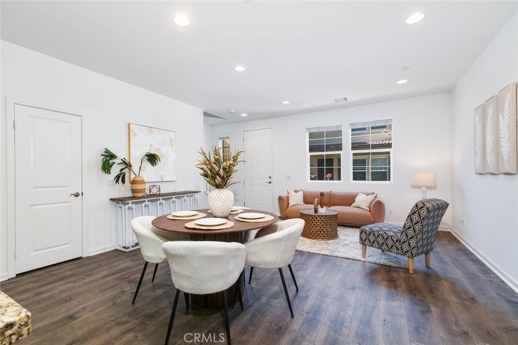 a dining room with furniture a wooden floor and kitchen