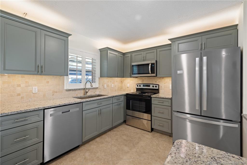 a kitchen with stainless steel appliances granite countertop a refrigerator sink and stove