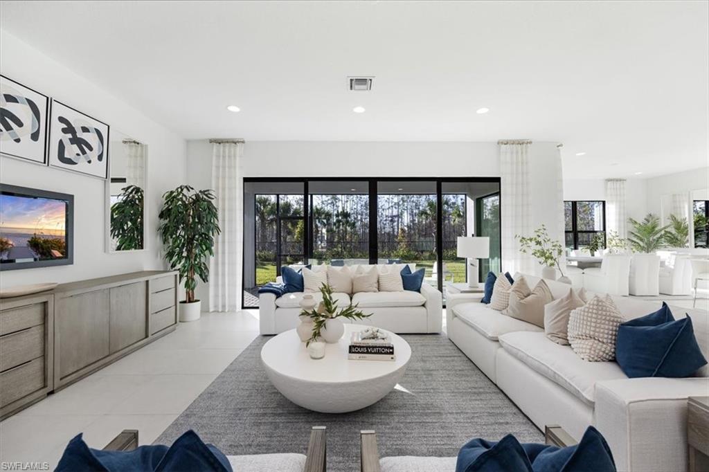 a living room with furniture large window and kitchen view