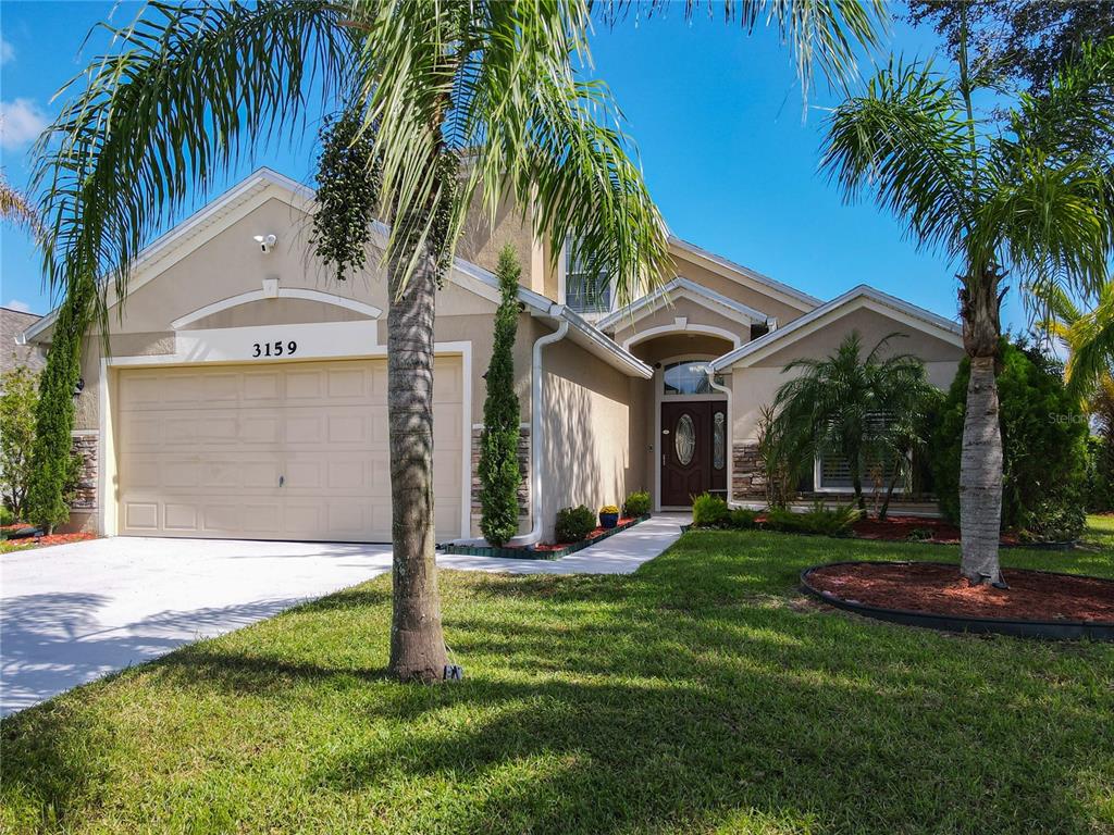 a view of a house with a yard and palm trees