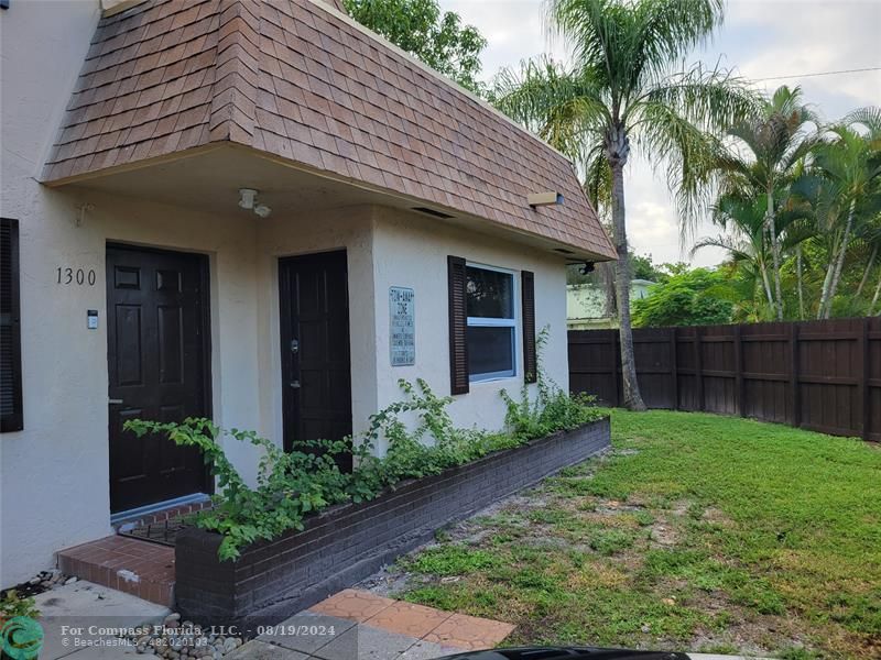 a view of a house with a small yard plants and palm trees