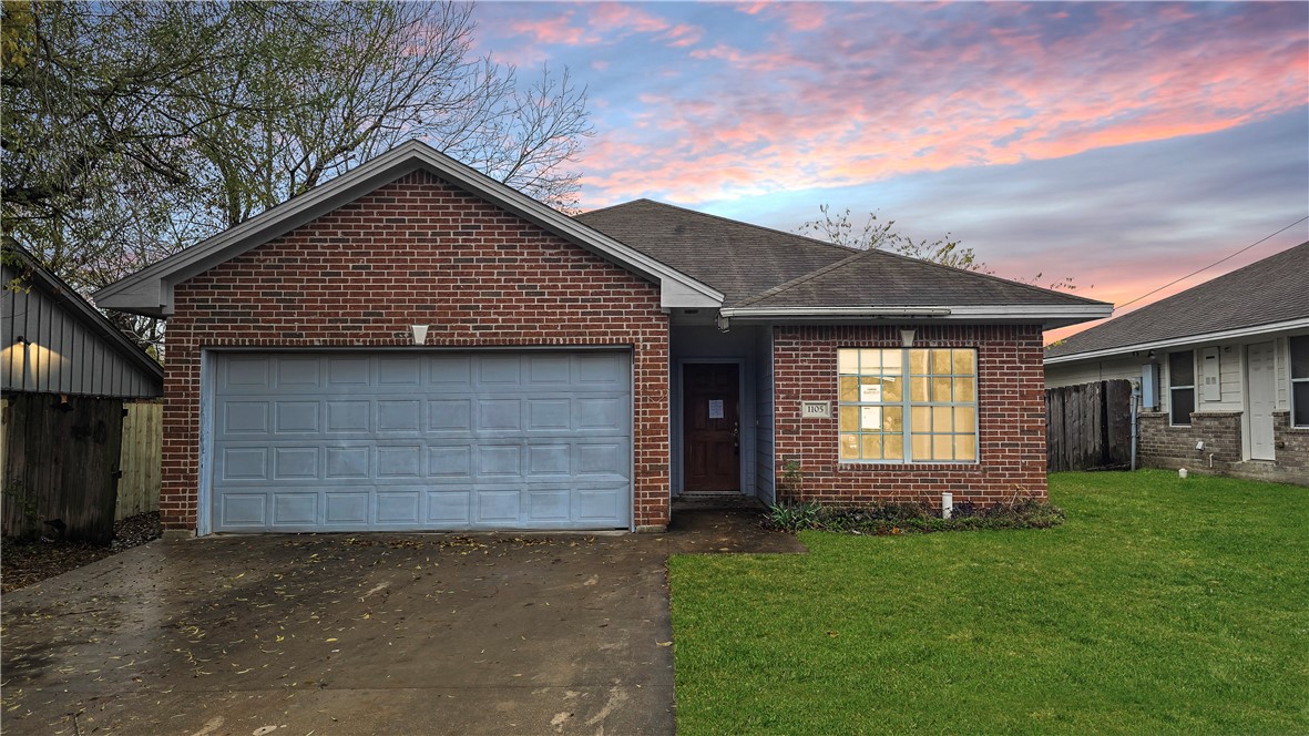 View of front of house featuring a yard and a gara