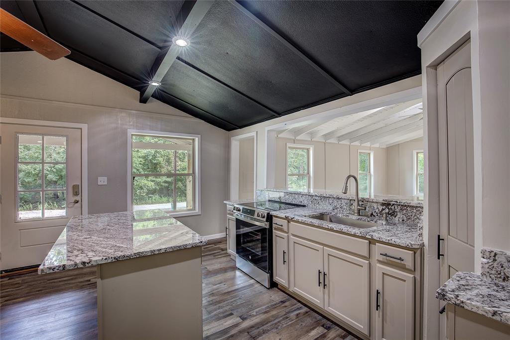 a kitchen with granite countertop stainless steel appliances a sink stove and cabinets