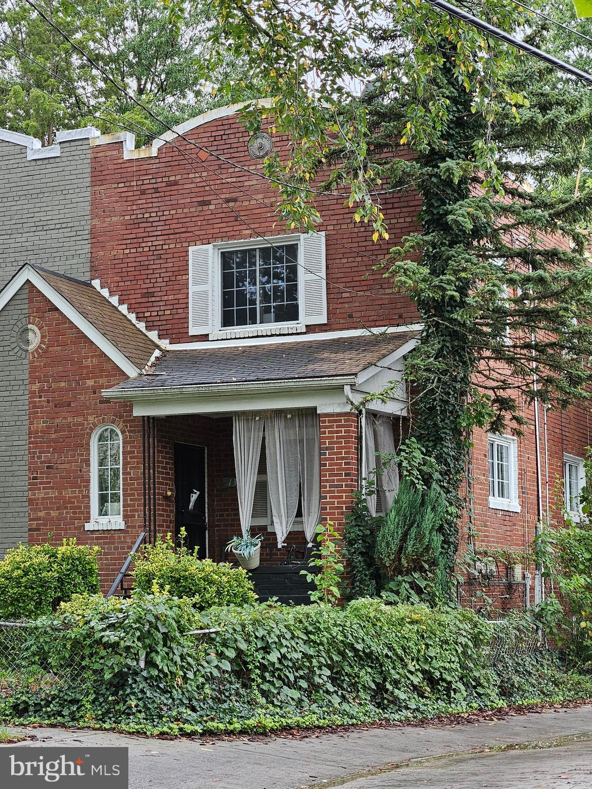 a view of a brick house with large windows and a large tree