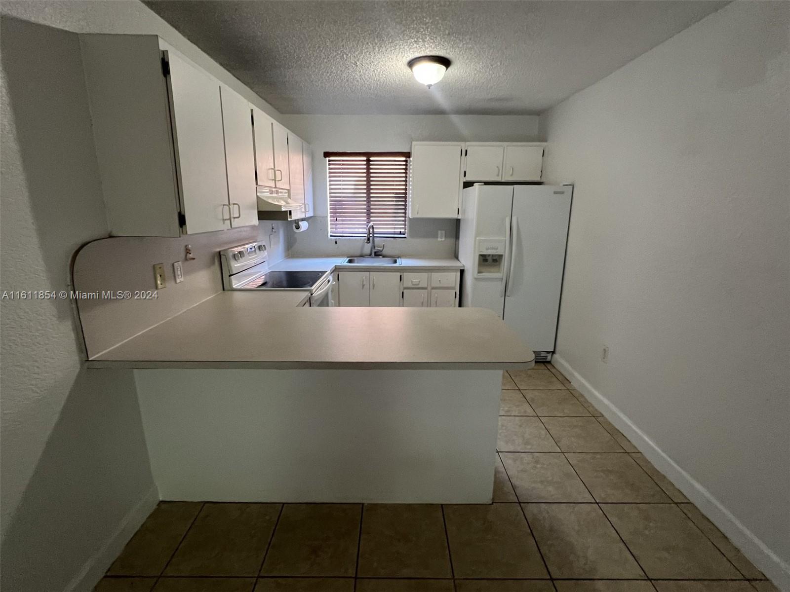 a kitchen with a sink a refrigerator and cabinets