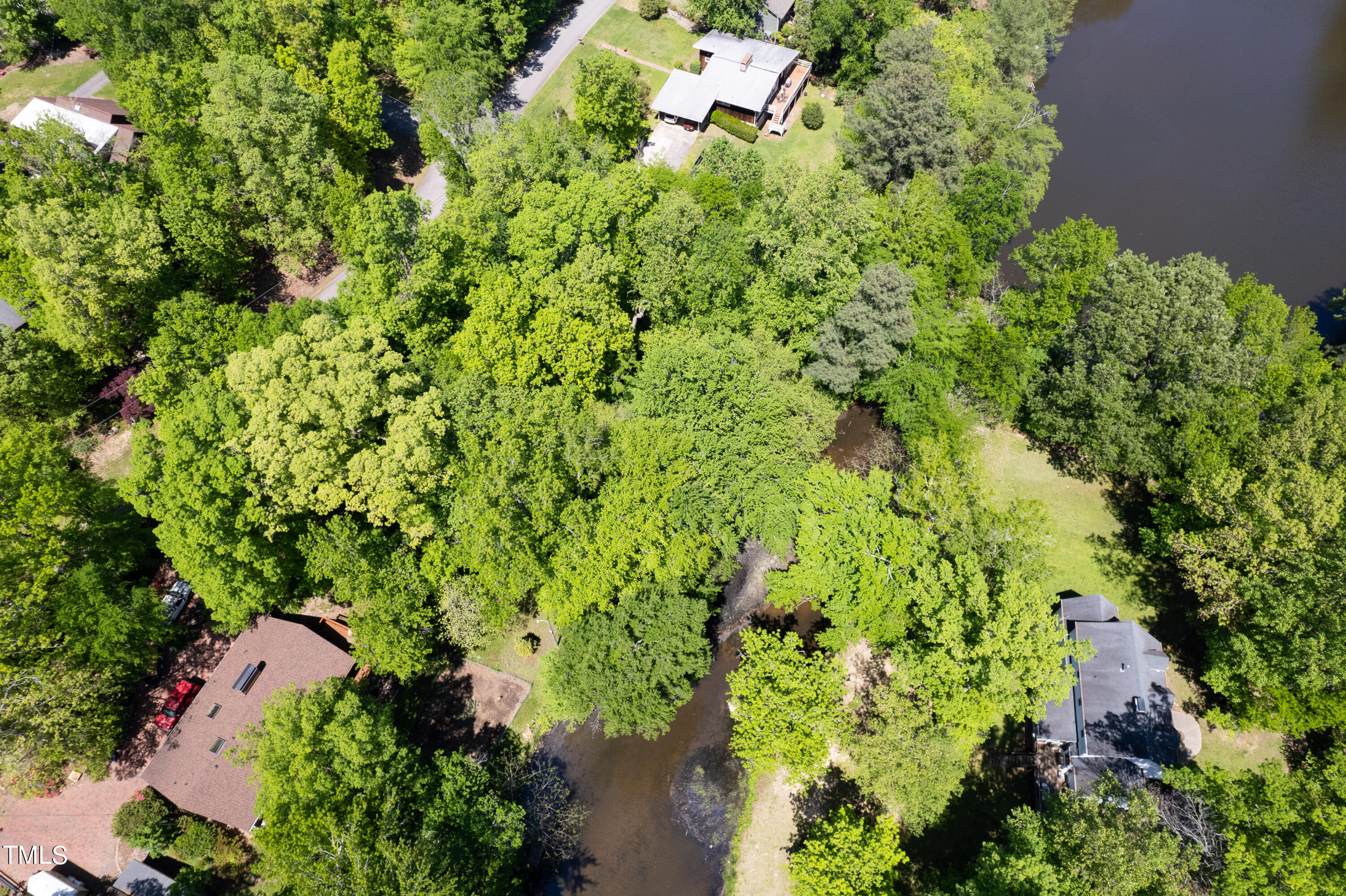 an aerial view of residential house with outdoor space and trees all around