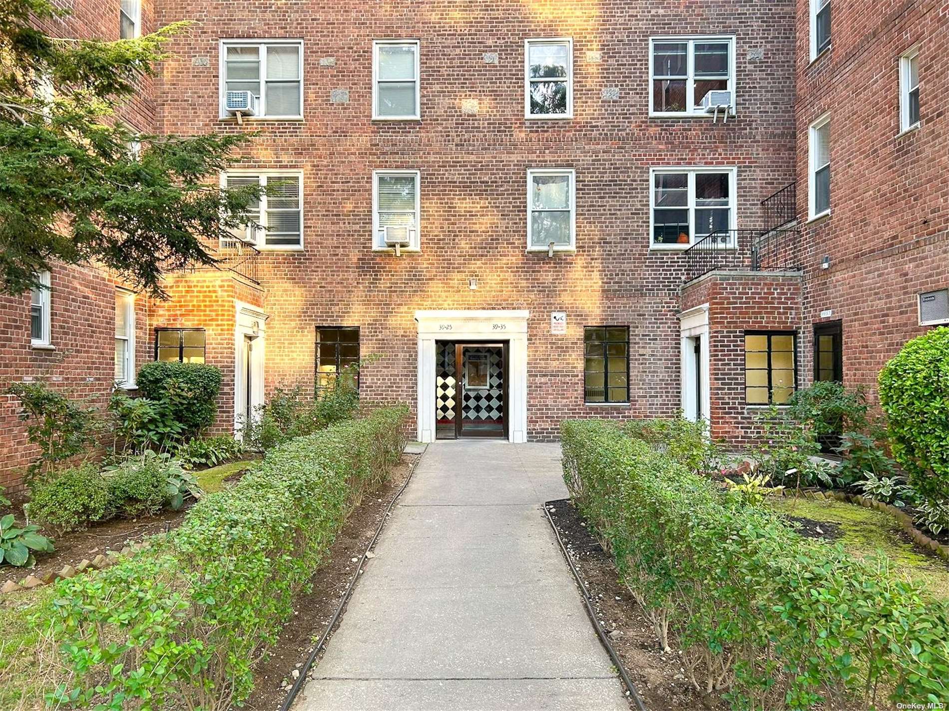 a front view of a brick house with a yard and potted plants