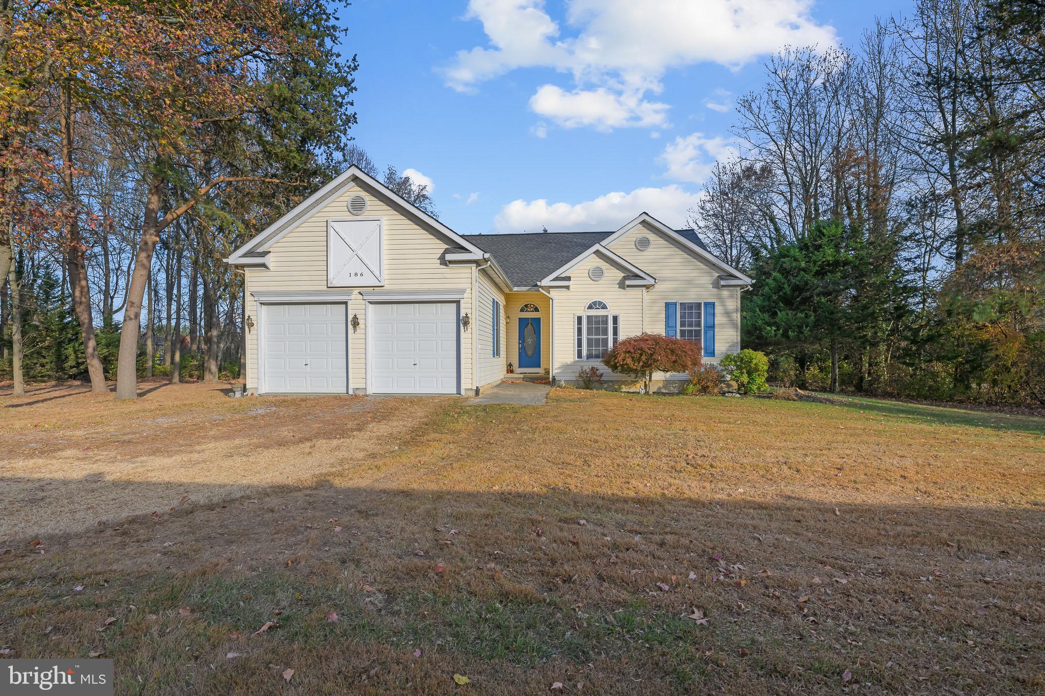 a front view of a house with a yard and large trees