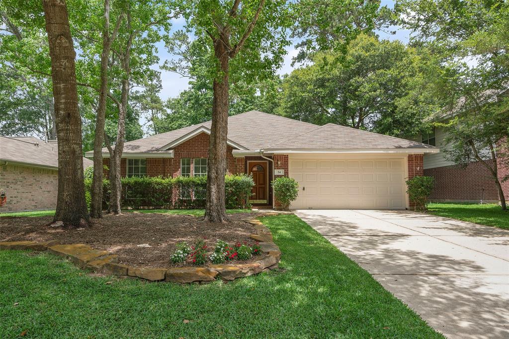 a view of a house with a yard plants and large tree