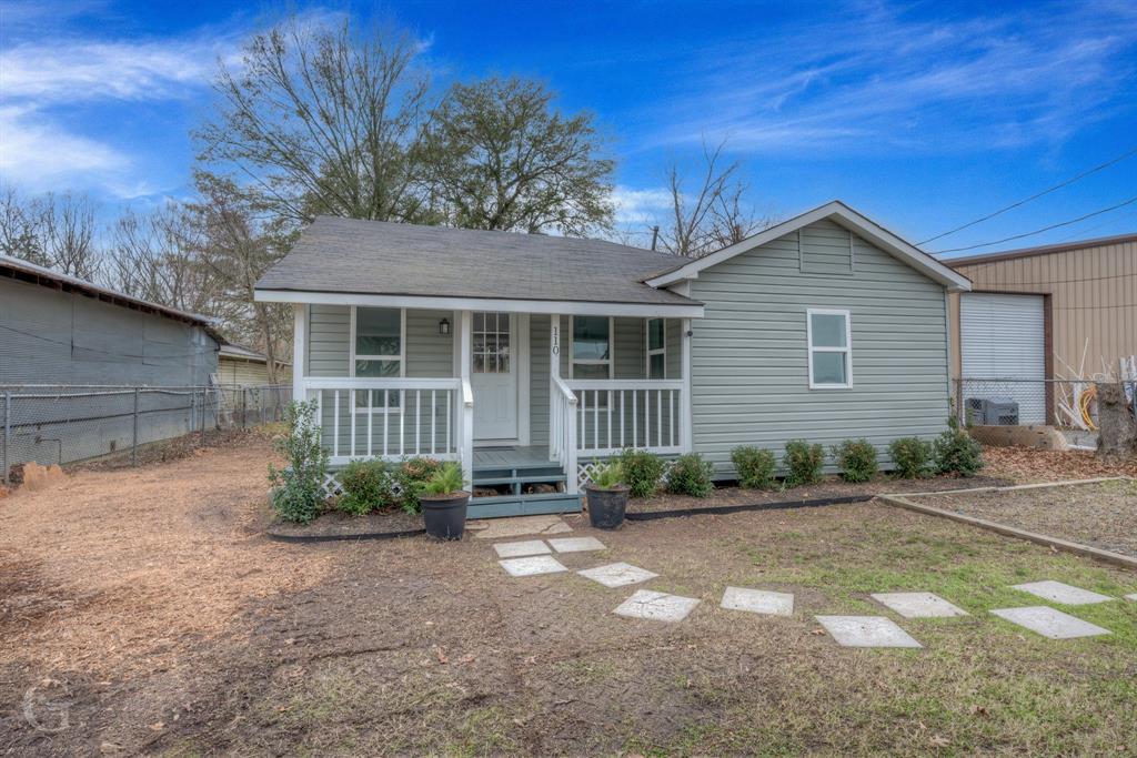 a front view of a house with a yard and potted plants