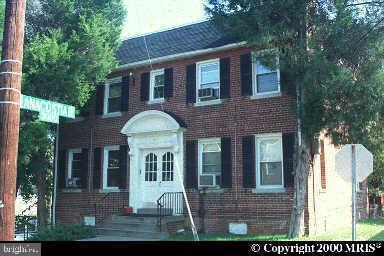 a view of a brick house with a yard potted plants and a table