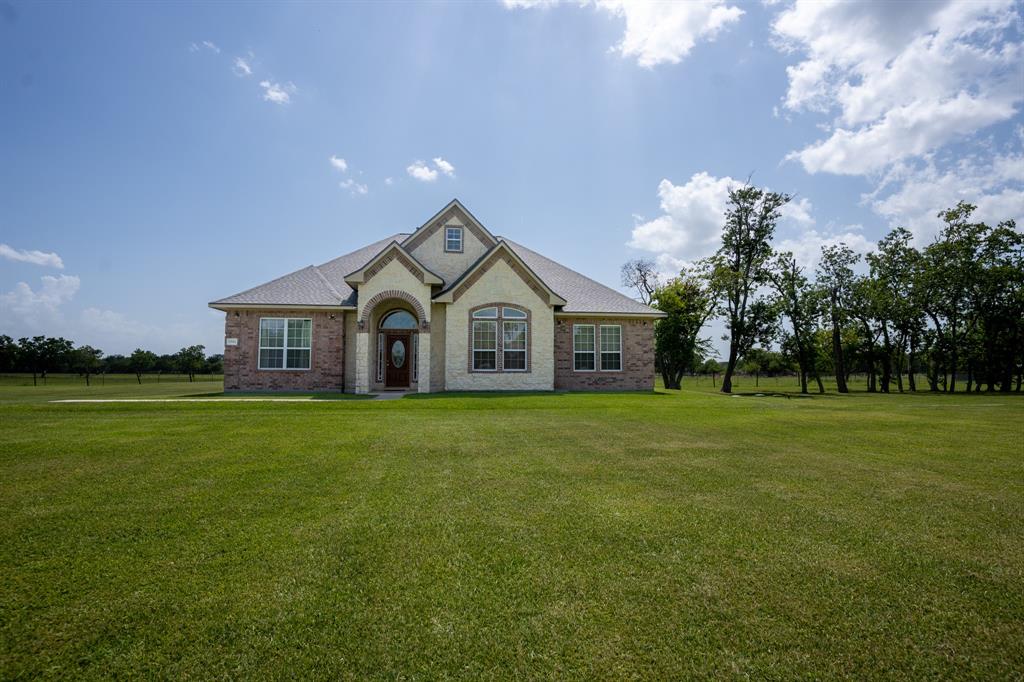 a front view of a house with a yard and trees