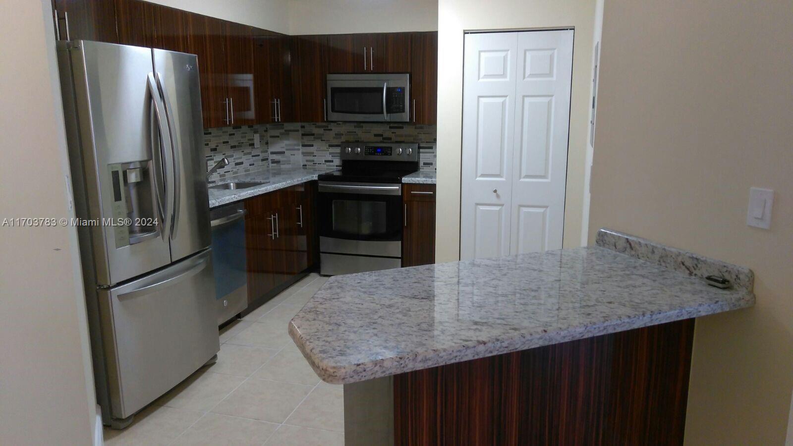 a kitchen with stainless steel appliances granite countertop a refrigerator and a sink