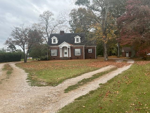 a front view of a house with a yard covered with snow and trees