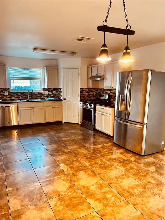 a large kitchen with stainless steel appliances granite countertop a stove a sink and a refrigerator