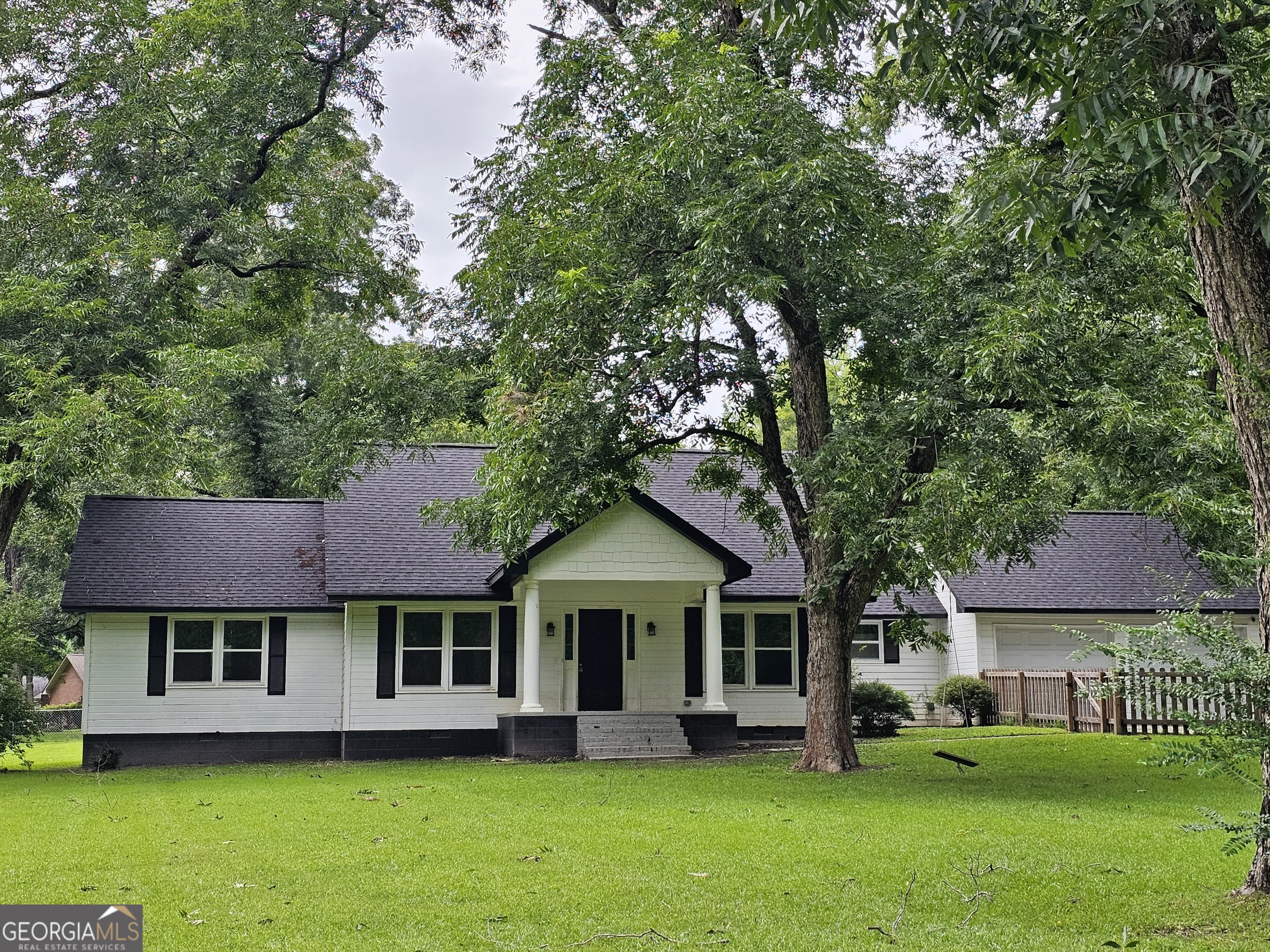 a front view of a house with a garden and trees